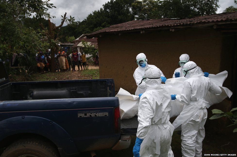 A burial team from the Liberian Red Cross carries the body of an Ebola victim from his home near Monrovia.