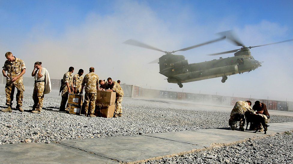 British soldiers from 16 Air Assault Brigade turn their heads as a Chinook lands on the helicopter pad at the Provincial Reconstruction Team base at Lashkar Gah in May 2006