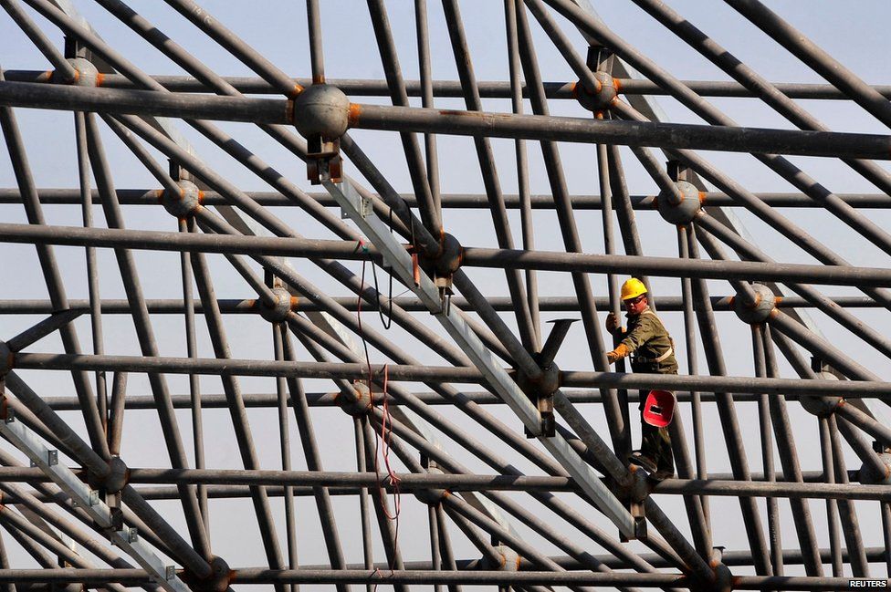 A man welds steel bars during construction of the roof of a new railway station in Urumuqi in China