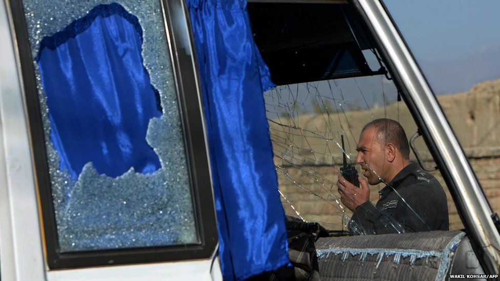 An Afghan policeman is seen through the shattered window of a military bus in Kabul