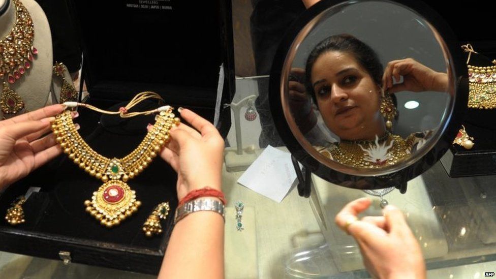 Indian shoppers try on gold jewellery at a jewellery store on Dhanteras in Amritsar on October 21, 2014.