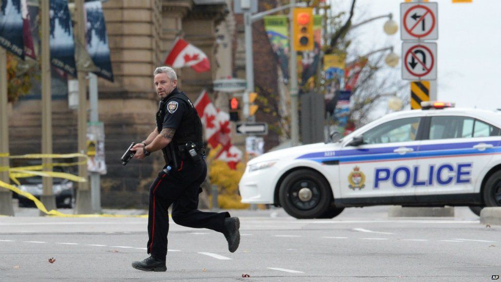 An Ottawa police officer runs with his weapon drawn outside Parliament Hill in Ottawa - 22 October 2014