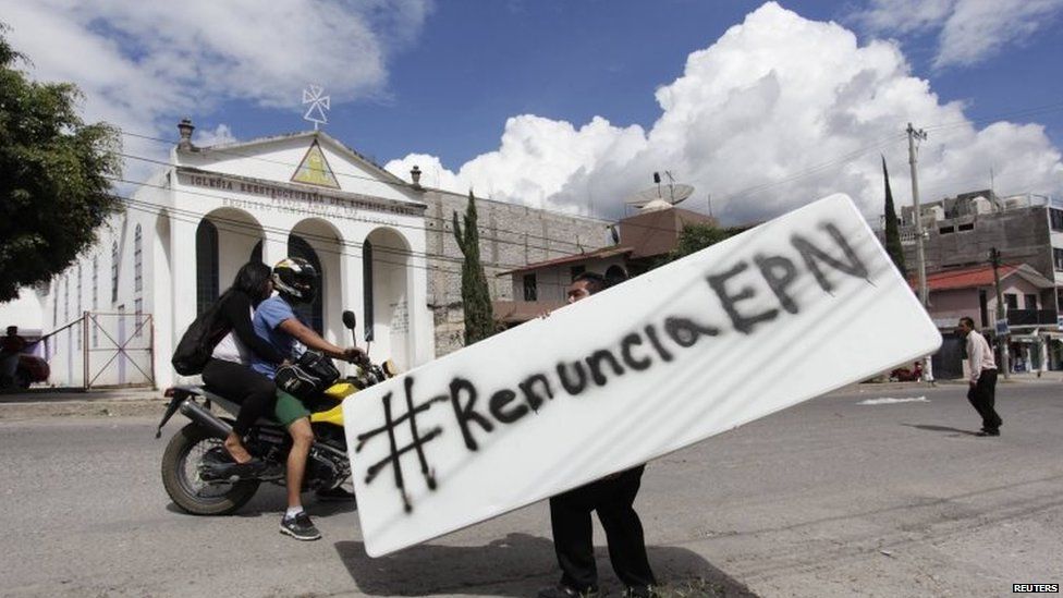 A man carries a sign, which reads: "Resign EPN" while walking in Chilpancingo on 11 November, 2014.