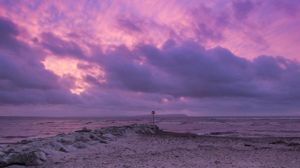 Bright purple skies from the morning sunrise, looking out to sea. The Isle of Wight is visible in the far background.