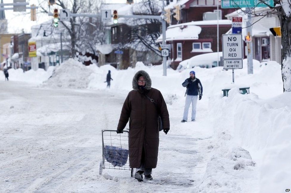 A woman walks down a snow-covered street in Buffalo, US