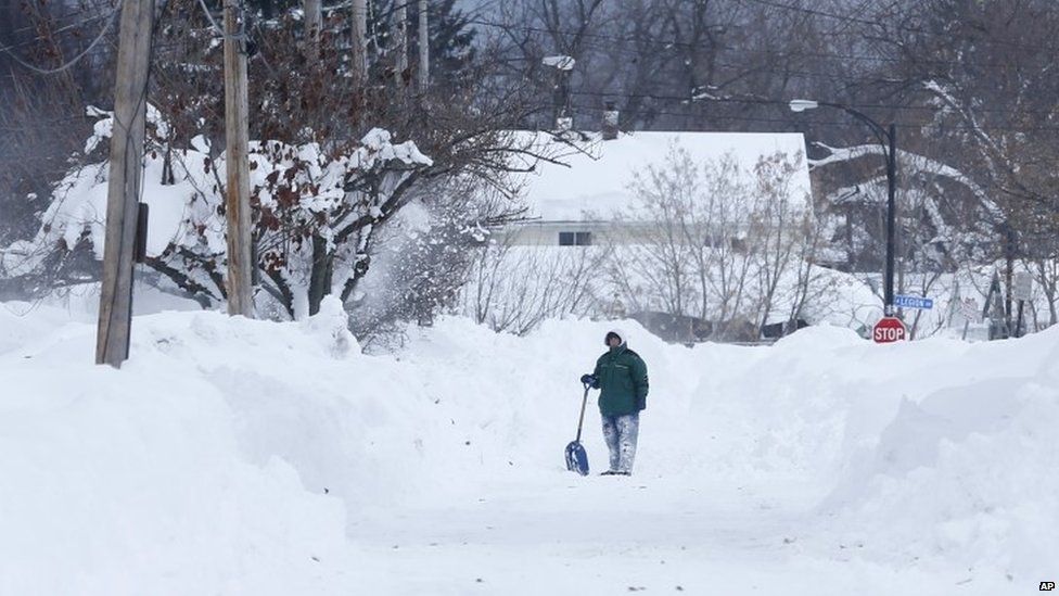A man takes a break from shovelling snow in Buffalo, US