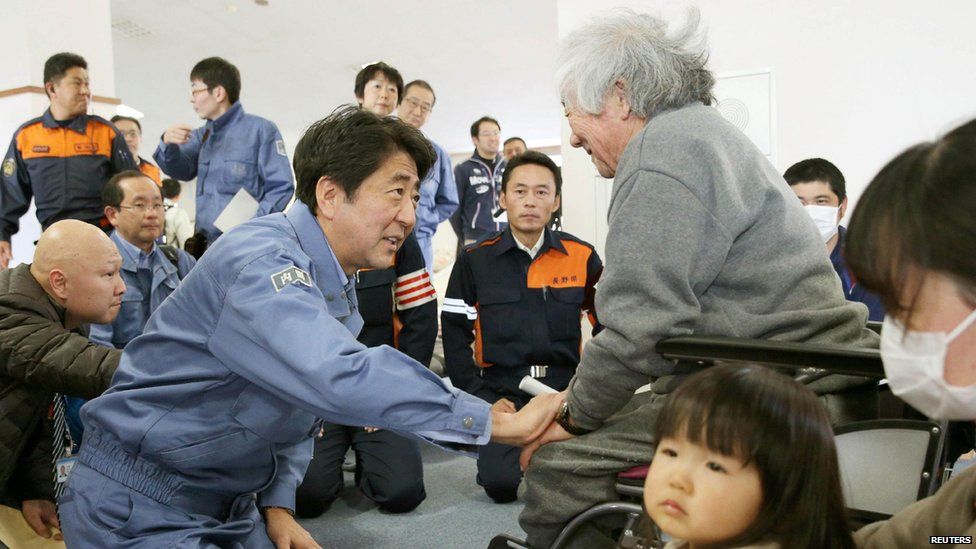 Japanese Prime Minister Shinzo Abe (L) meets victims of the earthquake which jolted central Japan on Saturday (22 November 2014)