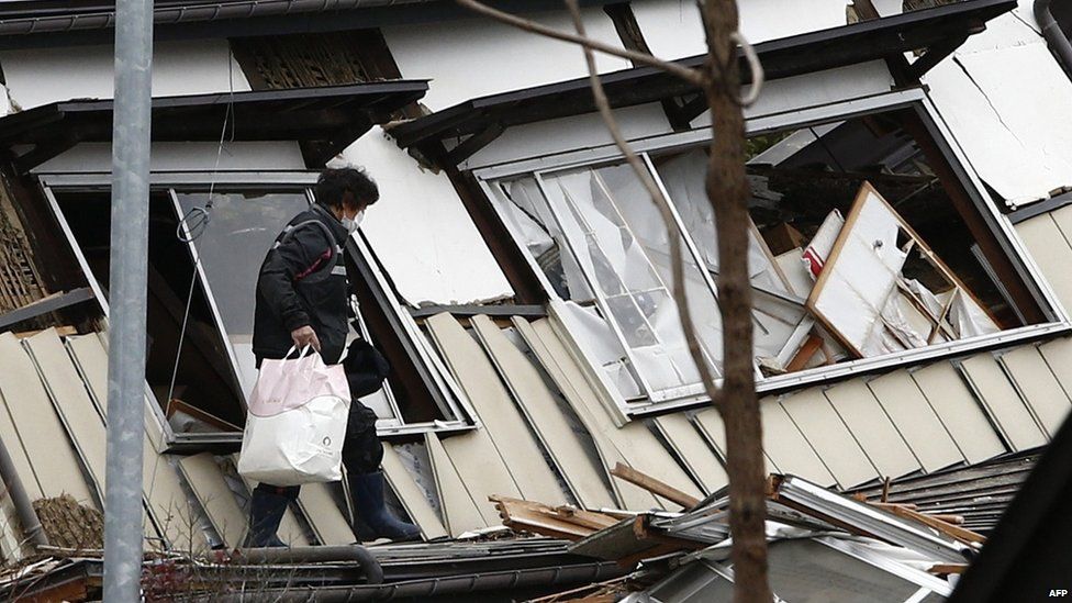 A resident leaves after picking up her belongings from her collapsed house after the earthquake hit the area of Hakuba, some 300km north-west of Tokyo, Nagano prefecture (23 November 2014)
