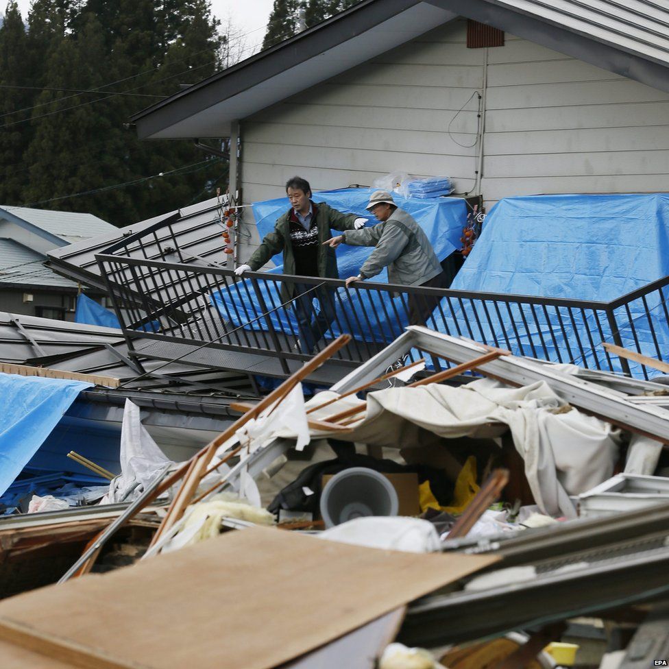 Residents cover pieces of their damaged home with plastic to protect it from snow following the quake in the ski resort village of Hakuba, central Japan (23 November 2014)