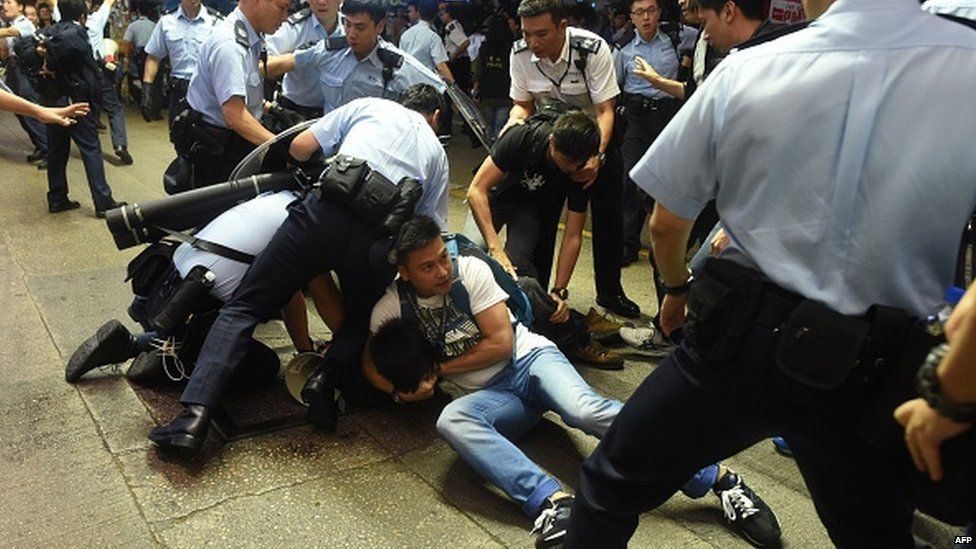 Police arrest a protester as they try to clear a road at a pro-democracy protest site in the Mongkok district of Hong Kong on November 25, 2014.