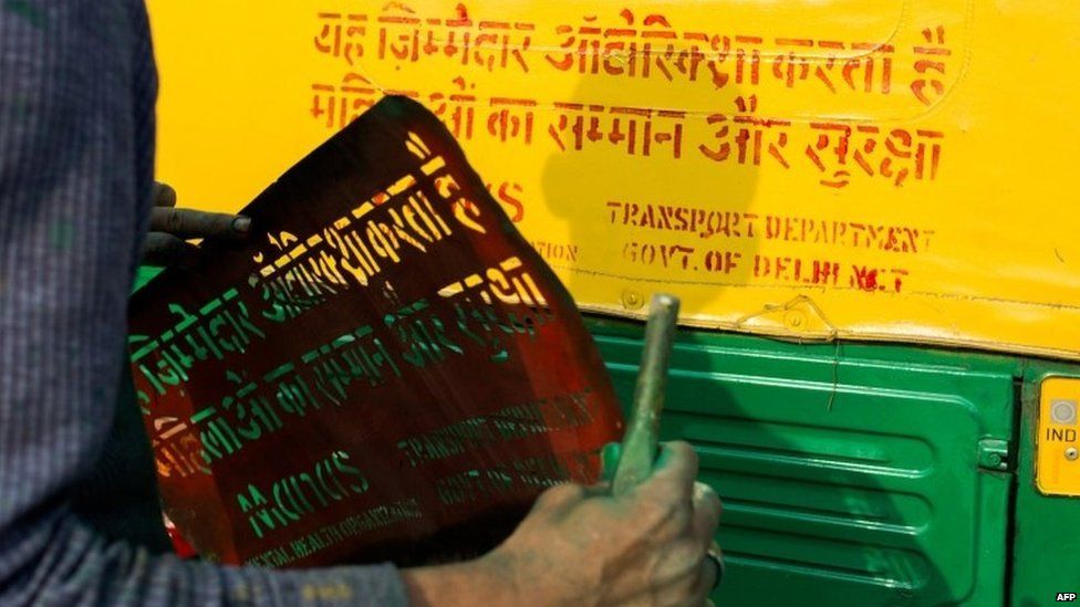 An Indian worker marks an auto-rickshaw with a sign confirming the driver has taken part in a gender sensitisation training programme at a city transport department centre on the outskirts of New Delhi on December 12, 2014.