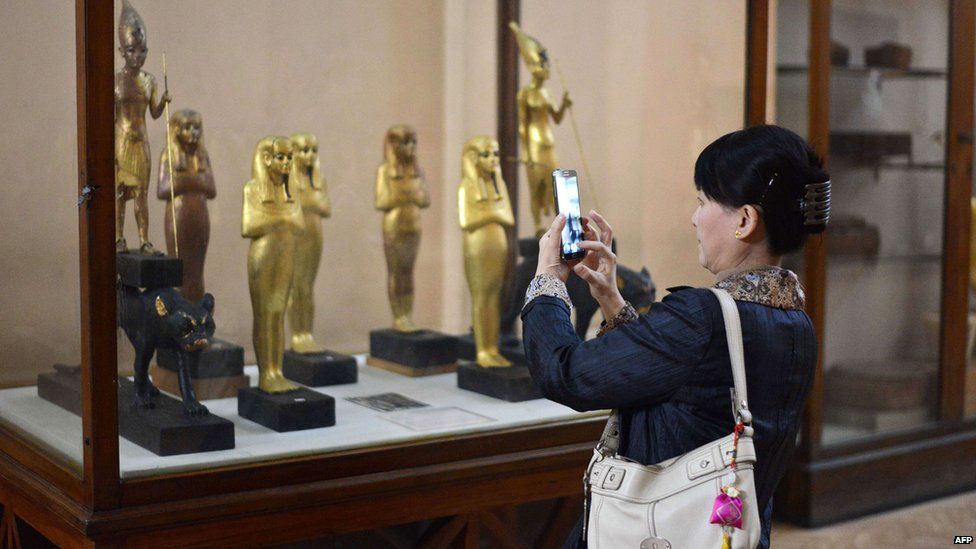 Woman taking photo of statues in case