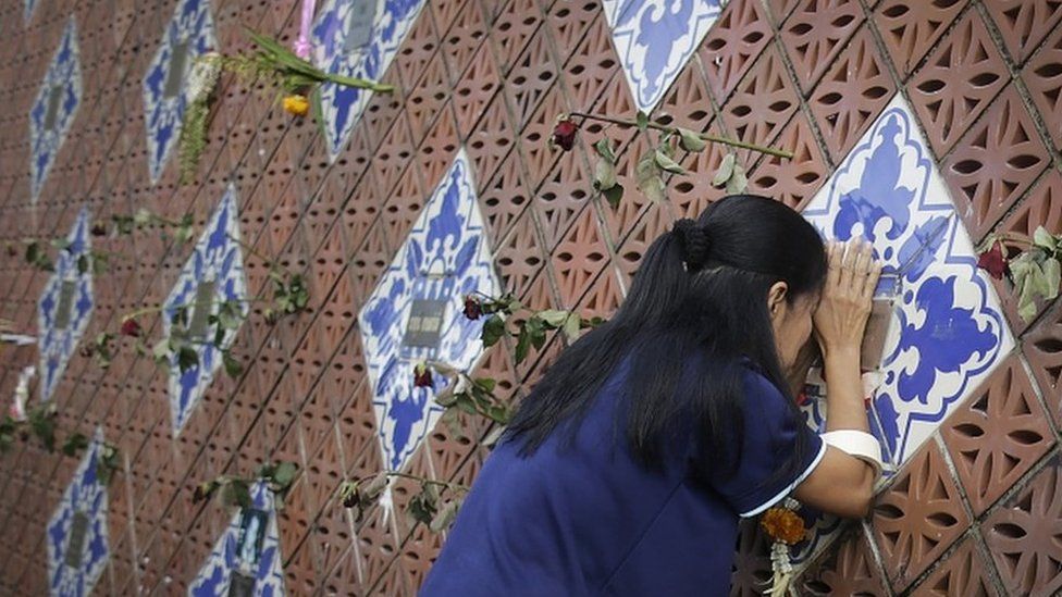 A woman offers prayers on a tiled memorial wall displaying names of the tsunami victims in Phang Nga, Thailand. Photo: 26 December 2014
