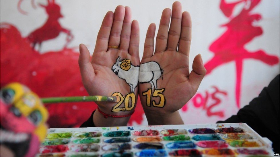 A college student with paintings of a sheep on their hands to welcome the new year, and to mark the coming "Year of the Sheep", in Liaocheng, in eastern China's Shandong province on 30 December 2014
