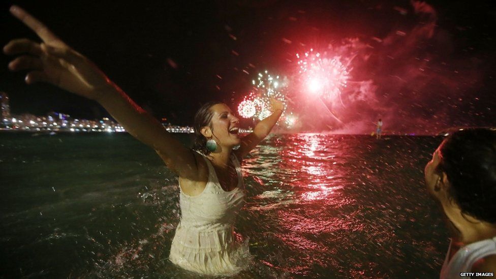 Revellers celebrate as fireworks explode during new year festivities on Copacabana Beach, Rio de Janeiro (01 December 2015)