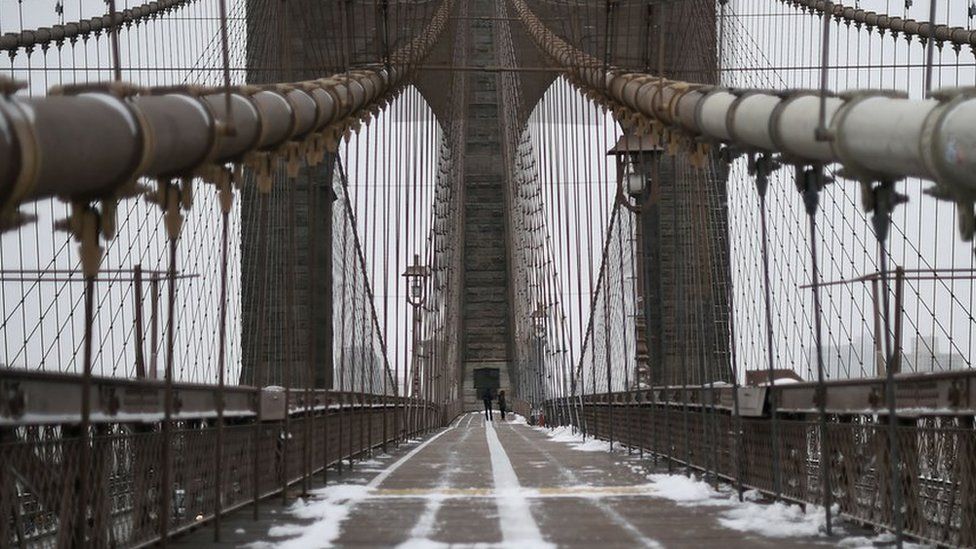 A couple walk on the Brooklyn Bridge in New York after a snowstorm