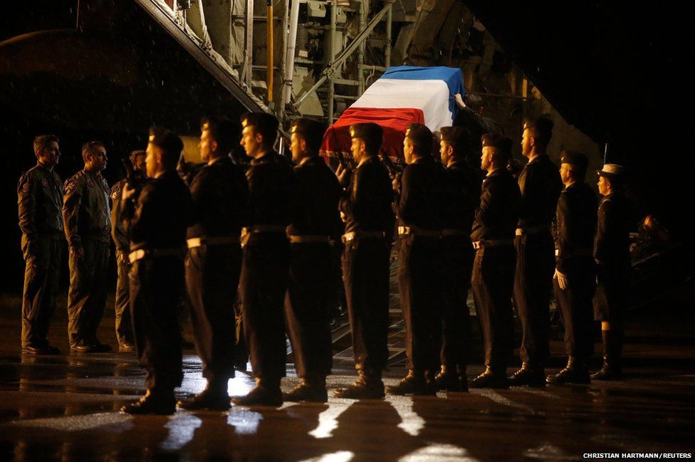 The flag-draped coffin of one of the nine French Air Force personnel is carried by pall-bearers as he arrives at the Nancy-Ochey Airbase, eastern France