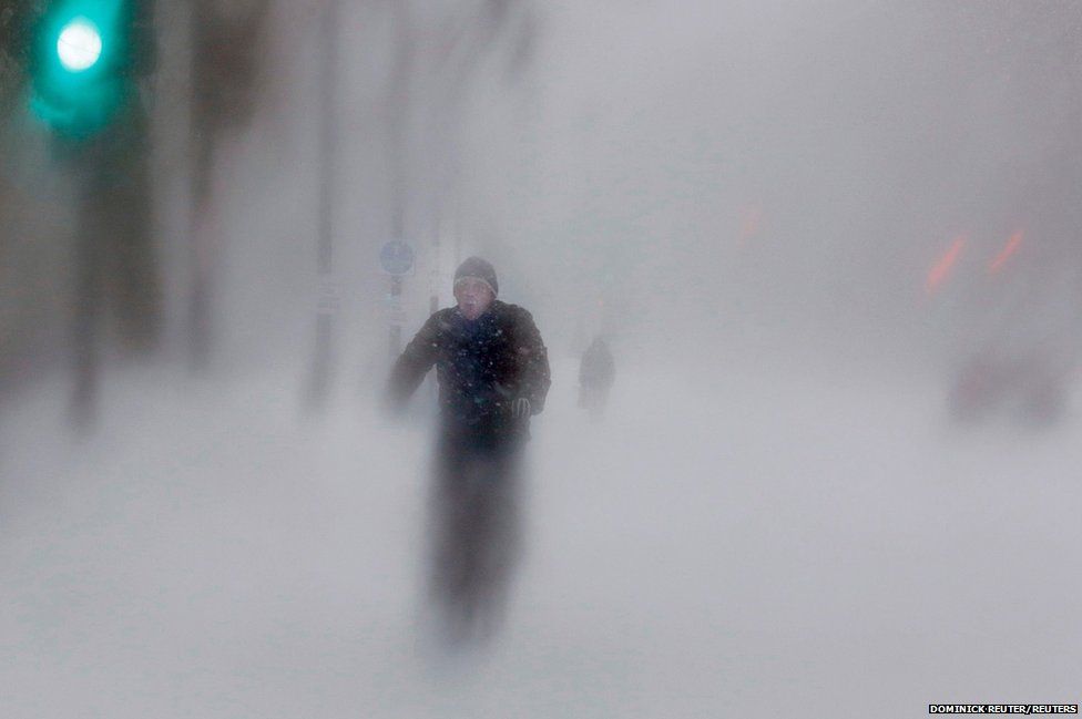 A man rides his bike up Beacon Street during a blizzard in Boston, Massachusetts