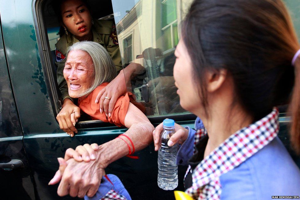 Eng Sokha holds her mother Nget Khun's hand as she is taken away in a police van