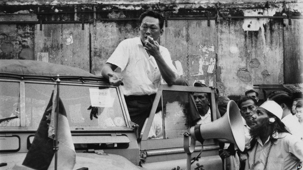 Singapore Prime Minister Lee Kuan Yew stands on the running board of a government vehicle in Singapore as he addressed a crowd in a slum area, in July 29, 1964. Yew, popular with the masses, asked for a halt in the racial strife that has struck the island city.