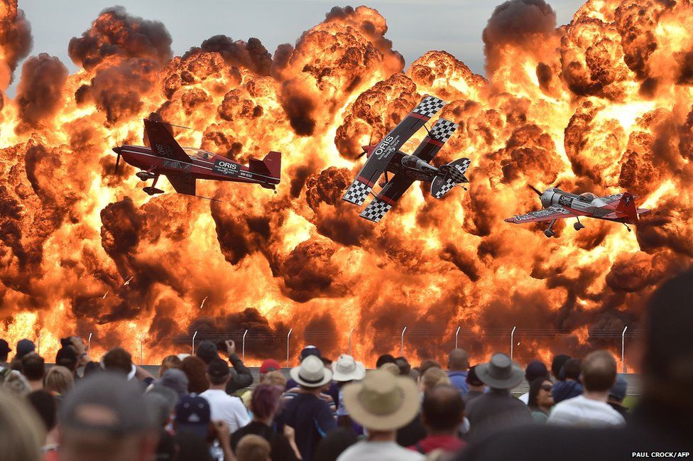 Aerobatic pilots fly in front of fire