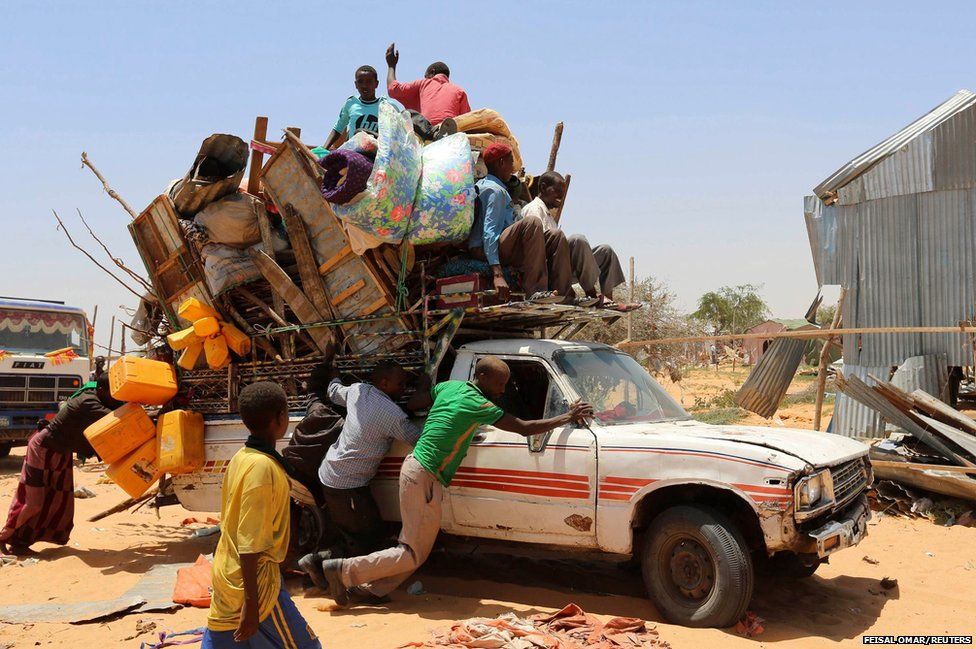 Displaced Somali families help push a truck carrying their belongings