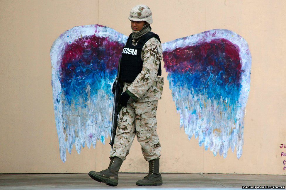 A soldier walks past graffiti depicting angel wings