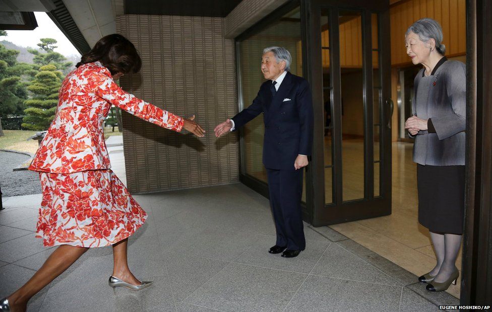 US first lady Michelle Obama (left) recovers from a stumble before shaking hands with Emperor Akihito