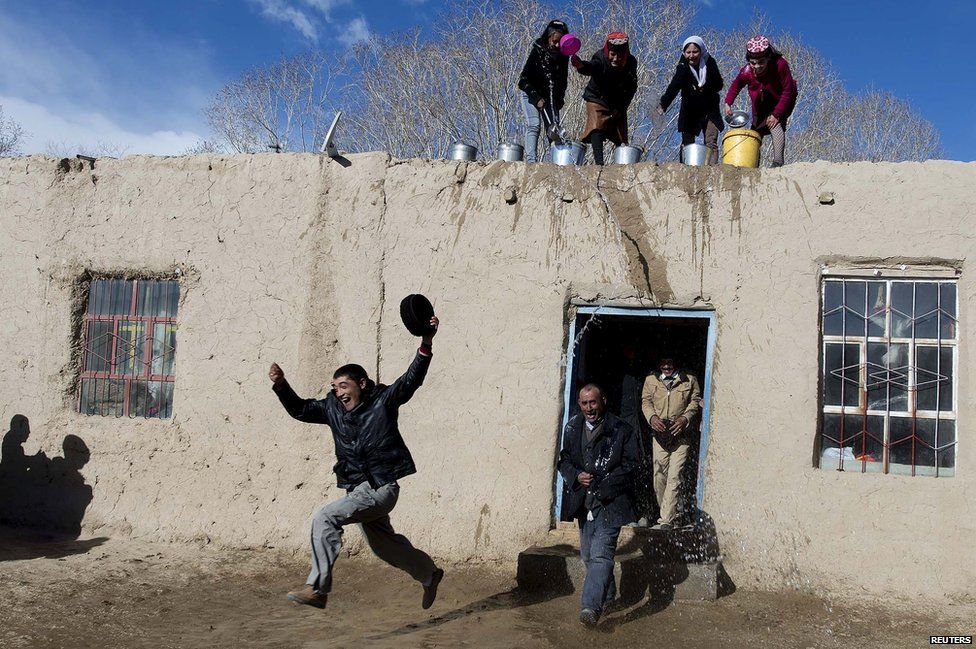 Tadjik women throw water on men from a roof top