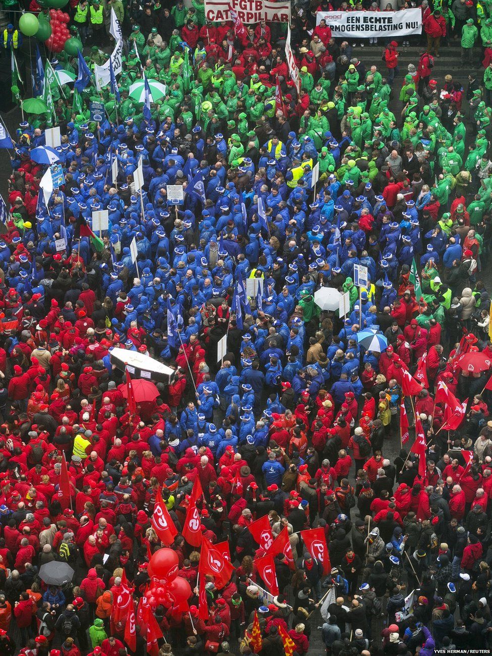 Protesters wearing red (Socialists), blue (Liberals) and green (Christian Democrats) vests gather in central Brussels during a trade union meeting