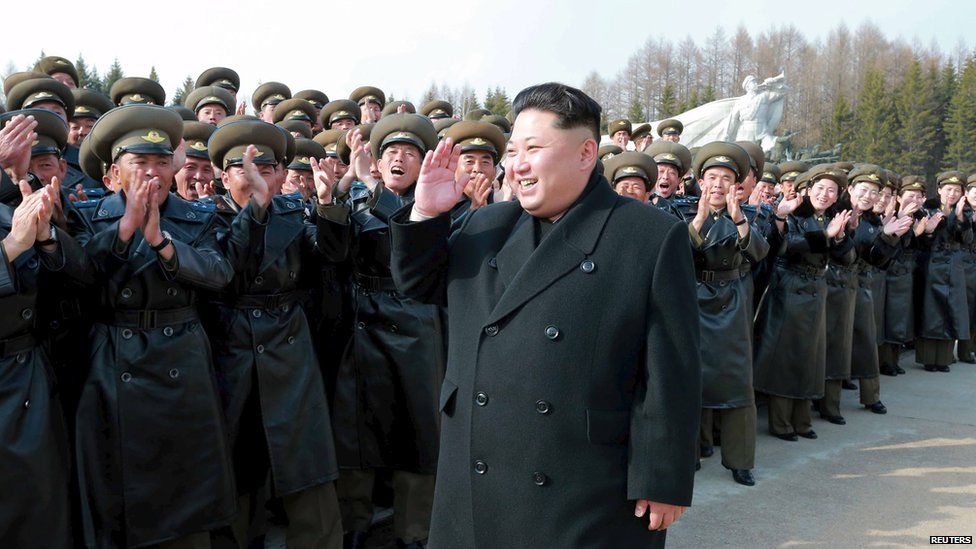 Kim Jong-Un, walking in front of troops, on top of a mountain