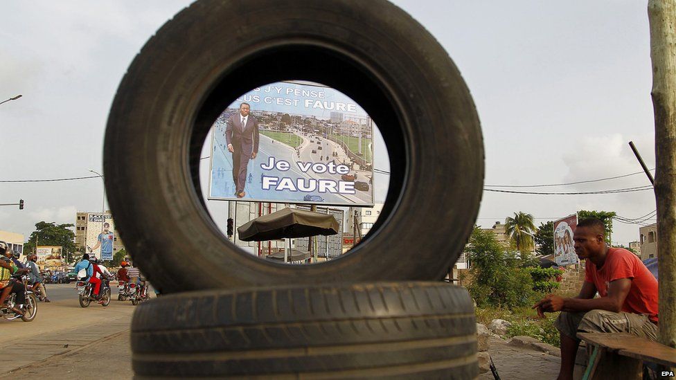 A campaign poster for Togo's President Faure Gnassingbe is seen through a huge tyre, Lome, Togo - Wednesday 22 April 2015