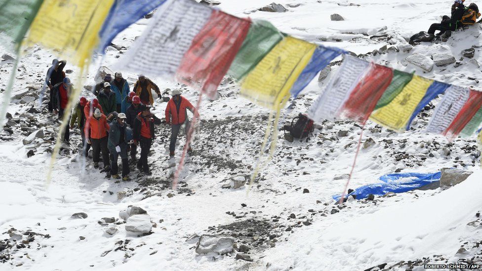 Rescue team personnel carry an injured person towards a waiting helicopter at Everest Base Camp (26 April 2015)