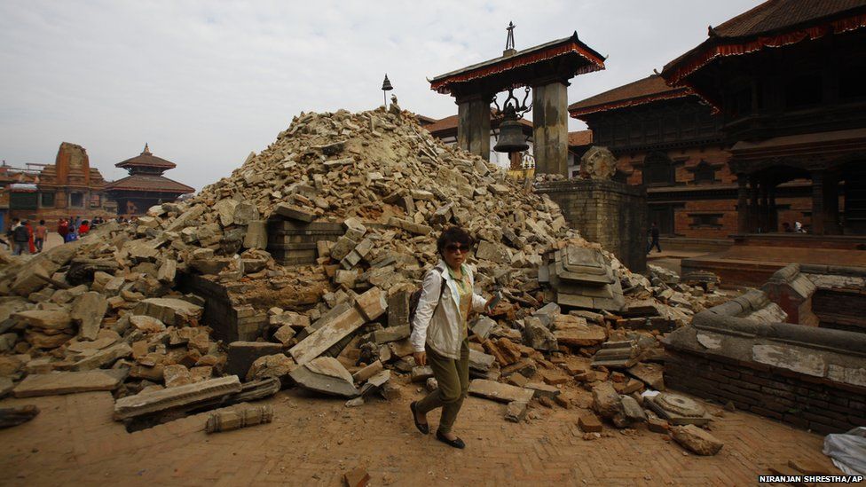 A Nepalese woman walks past a collapsed temple in Bhaktapur Durbar Square in Kathmandu (26 April 2015)