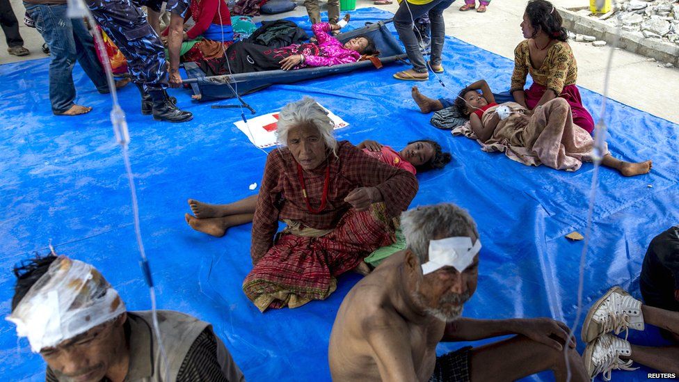 Earthquake victims sit on a tarpaulin as they receive medical treatment outside Dhading hospital in Dhading Besi (27 April 2015)
