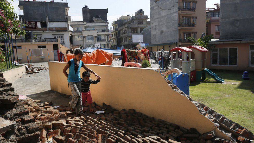 A young girl walks with a boy over a collapsed school playground in Kathmandu (27 April 2015)