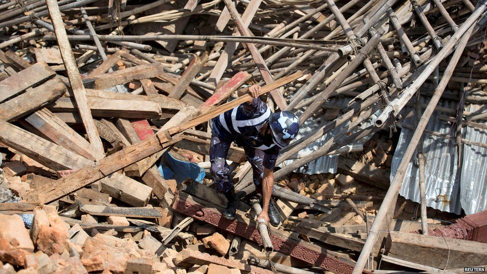 A Nepalese policeman tries to clear the rubble with his hands while looking for survivors at the compound of a collapsed temple in Kathmandu (27 April 2015)