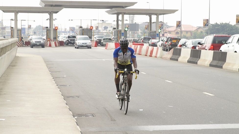 A cyclist by a toll bridge in Lagos, Nigeria