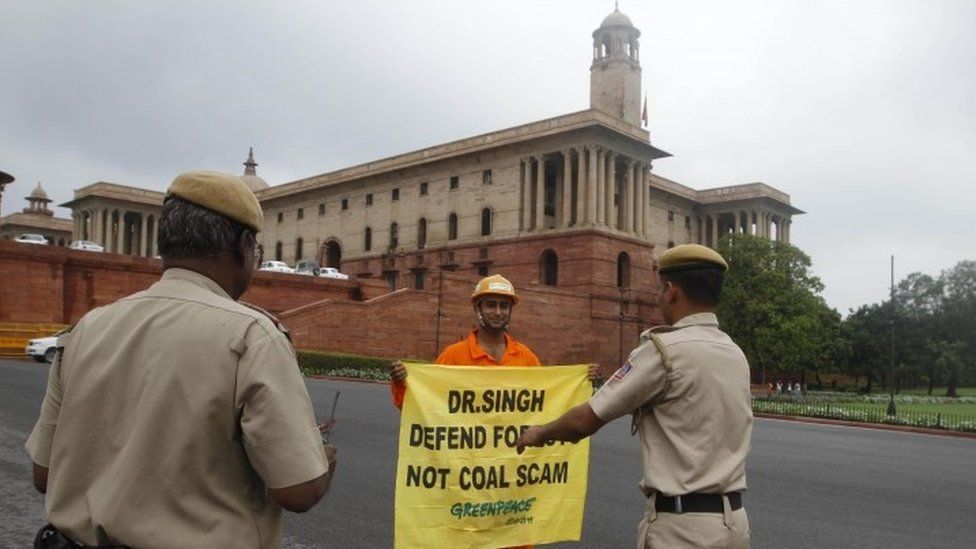 Indian policemen prepare to remove a Greenpeace activist as he holds a banner near the area of government offices and the Indian Parliament in New Delhi in 2012