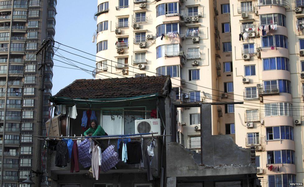 A woman stands at the balcony of her house in downtown Shanghai