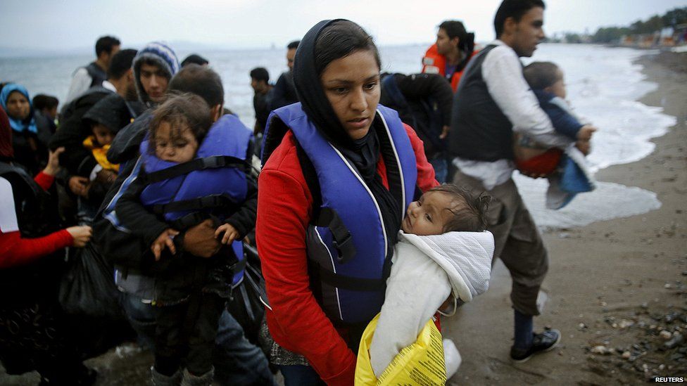 Migrants, including babies and children, arrive on the beach by boat