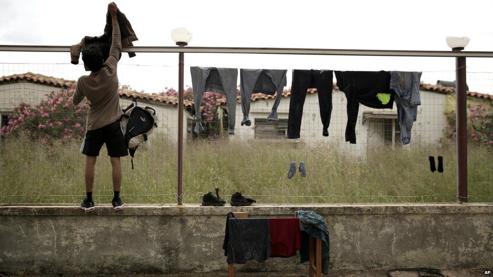 A young boy hangs clothes on a fence