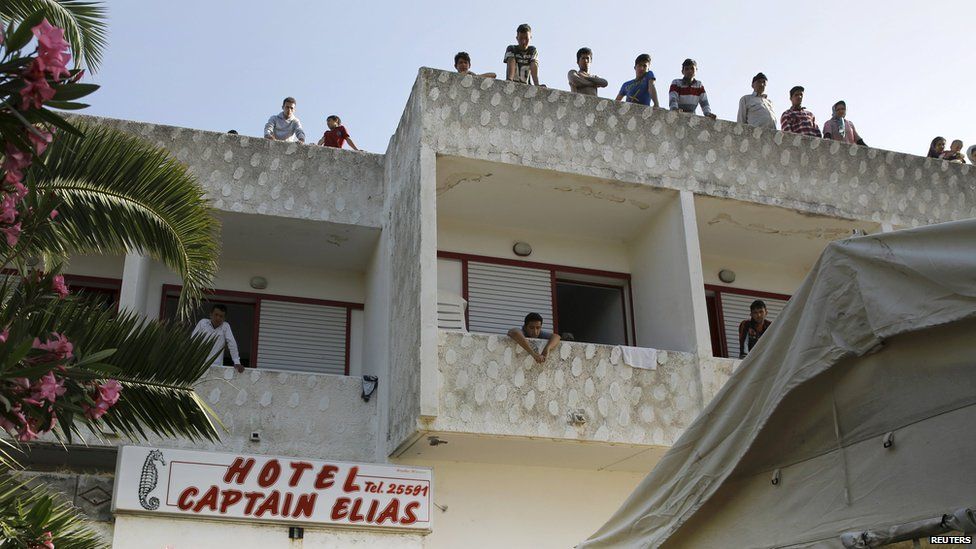Migrants stand on the roof of the former hotel where they are staying