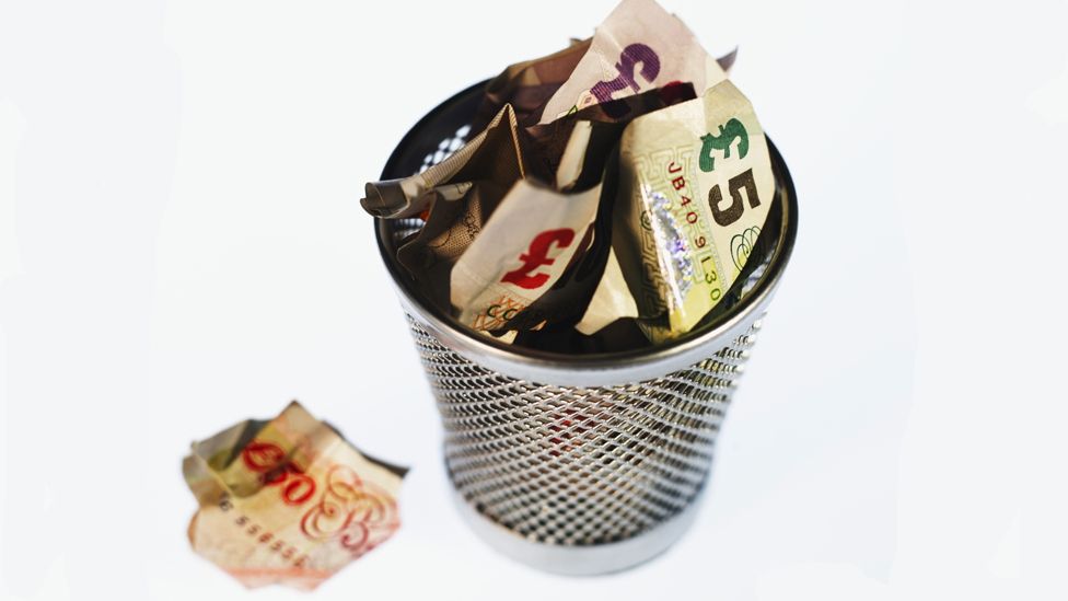 Wastepaper bin filled with money