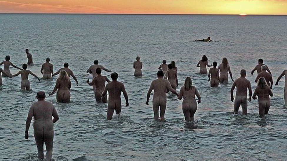 Nudists take part in the annual North East Skinny Dip as the sun rises at Druridge Bay in Northumberland.