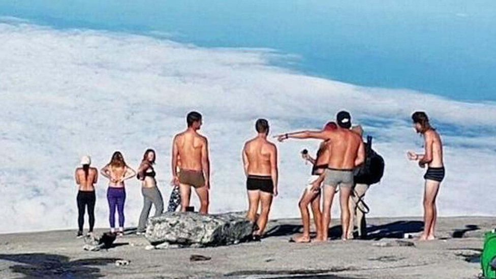 Hundreds of nudist people running into the sea naked