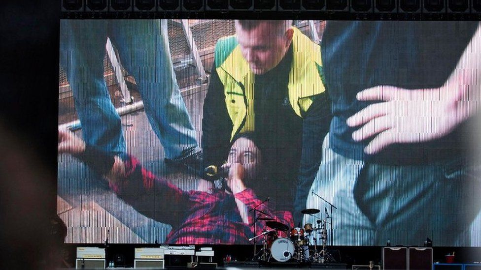Dave Grohl is shown on the TV screen after his fall