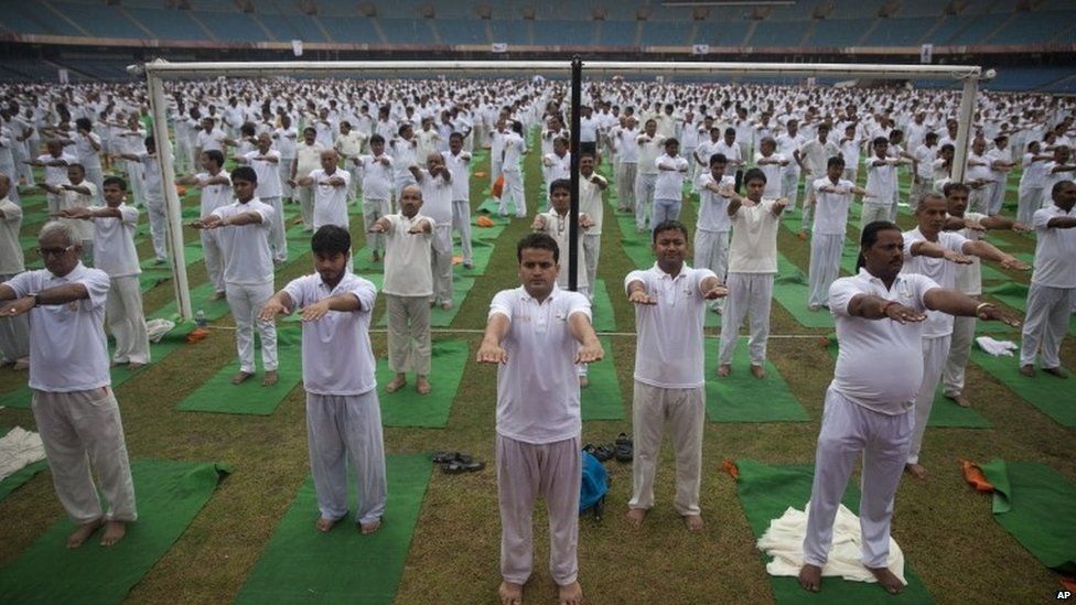 Indians stretch as they attend a yoga session in the rain in New Delhi, India, Sunday, June 14, 2015.