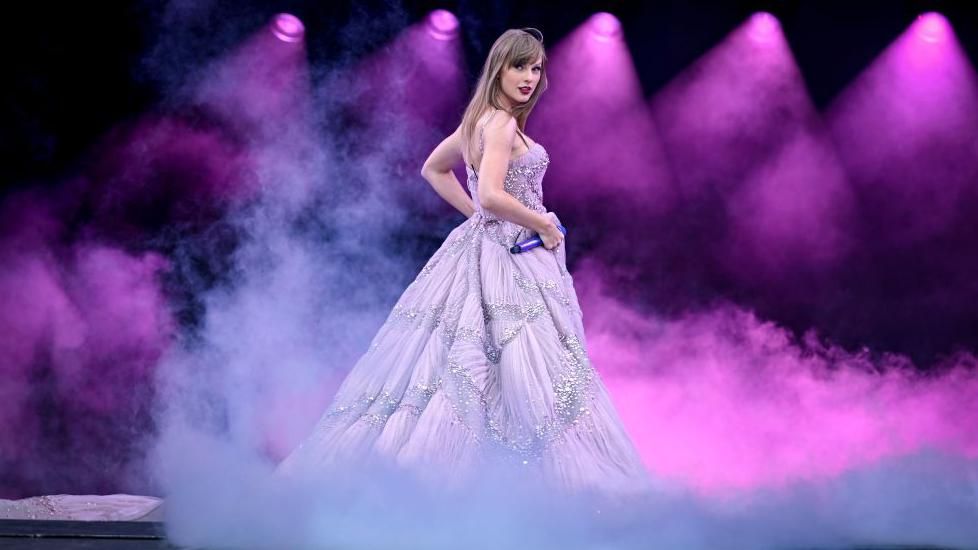Taylor Swift in a purple dress on stage.