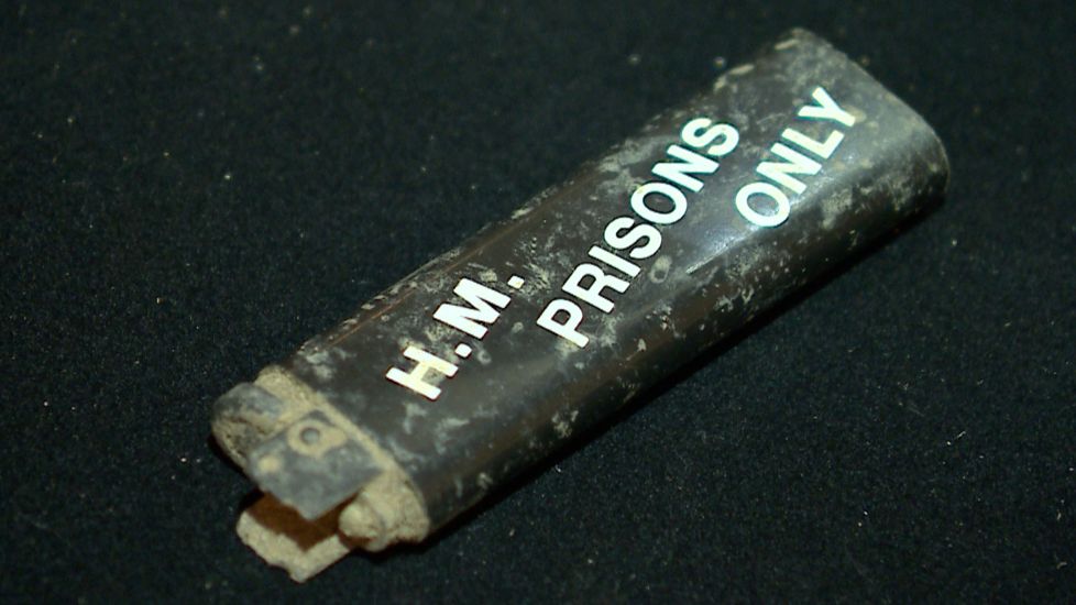 An black, rusty lighter with hm prisons only written on it in white letters